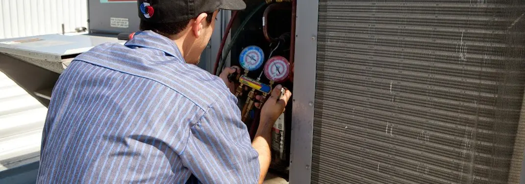HVAC technician servicing a condenser unit in Wheeling